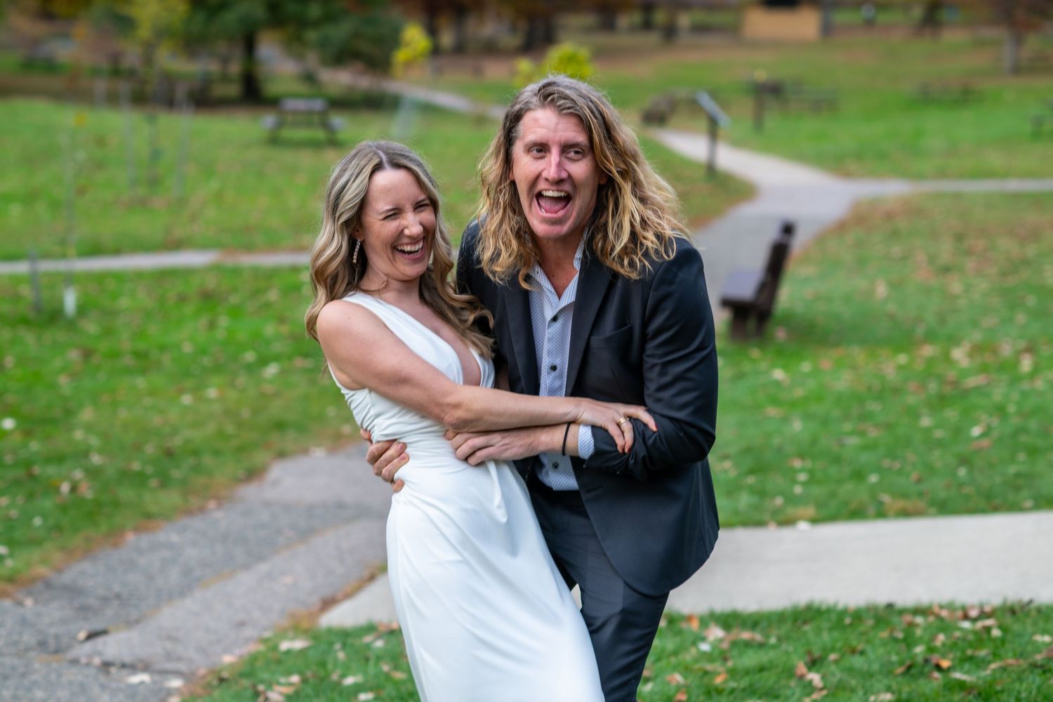 Couple shares joyful moments together during outdoor photo session in a green park setting.