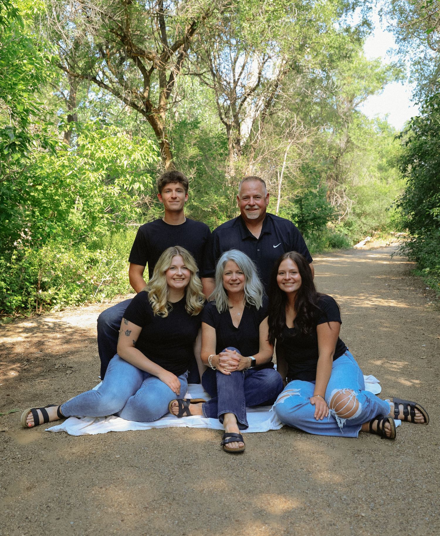 Family group photo session with everyone wearing black clothes in outdoor park setting.