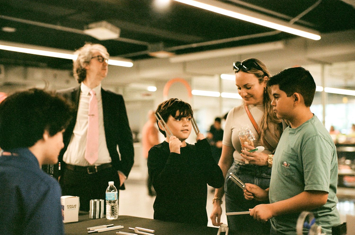 Group of people having an animated conversation in an indoor venue with fluorescent lighting.