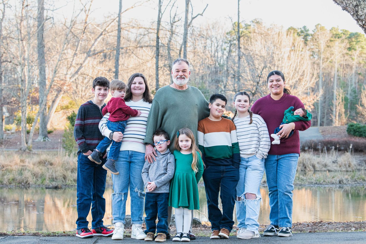 Grandfather posing with all his children in a beautiful park, capturing a heartwarming family moment together in nature.