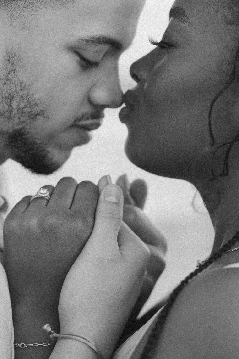 An intimate black and white portrait of a couple about to kiss.
