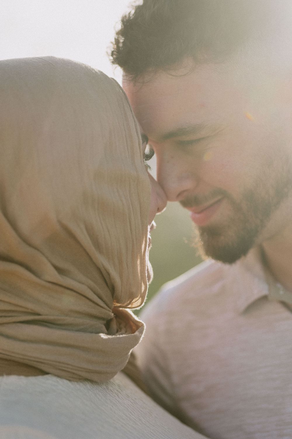 Intimate close-up portrait of a couple sharing a tender moment in warm sunlight.