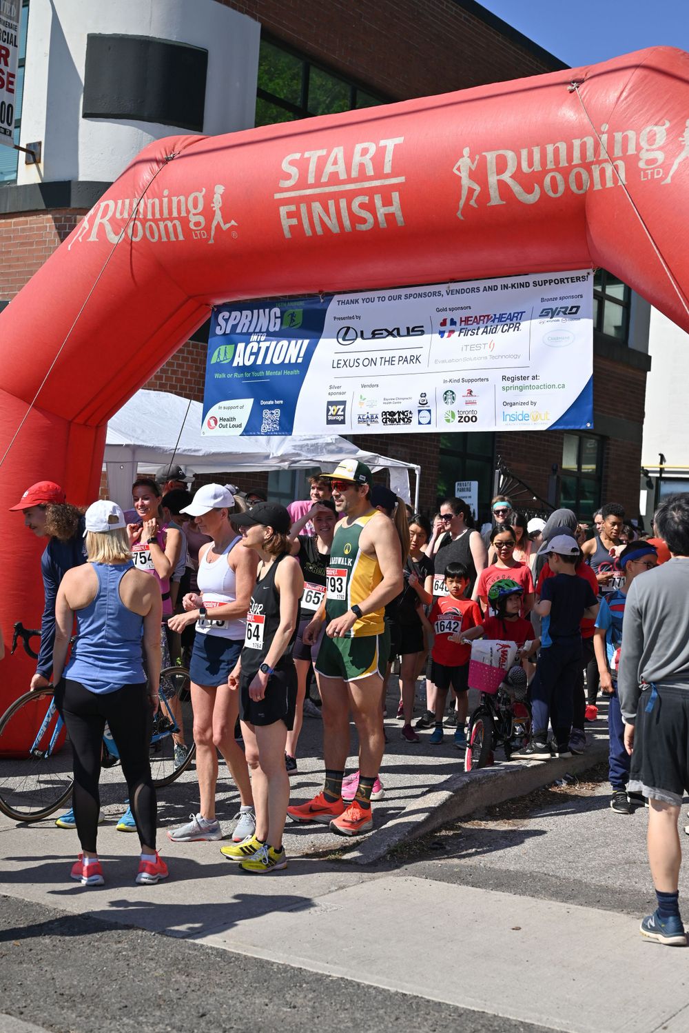 Runners gather under a large red inflatable start/finish arch at a Running Room race event.