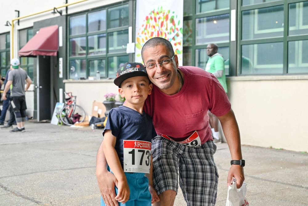 A smiling pair stands together outdoors near a building entrance during what appears to be a sporting event.