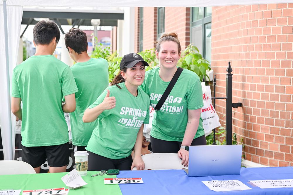 Event staff in bright green t-shirts working at a registration table with branded banners.