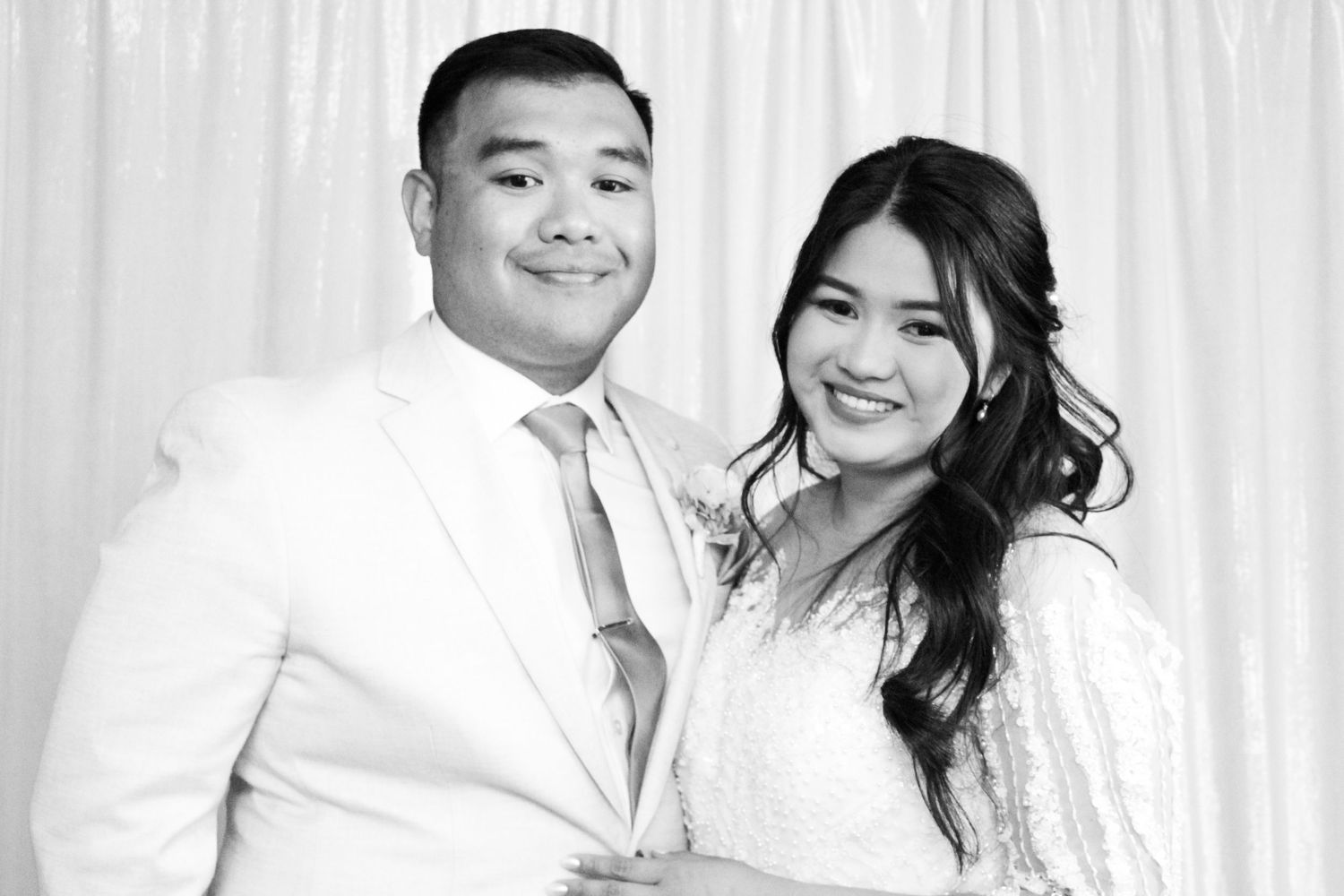 Black and white portrait of newlyweds in formal wedding attire smiling together.