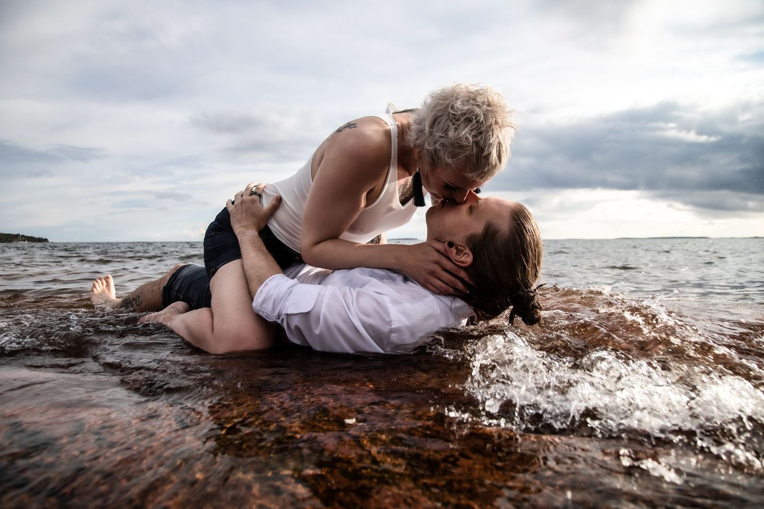 Romantic coastal scene with couple embracing on rocky shore.