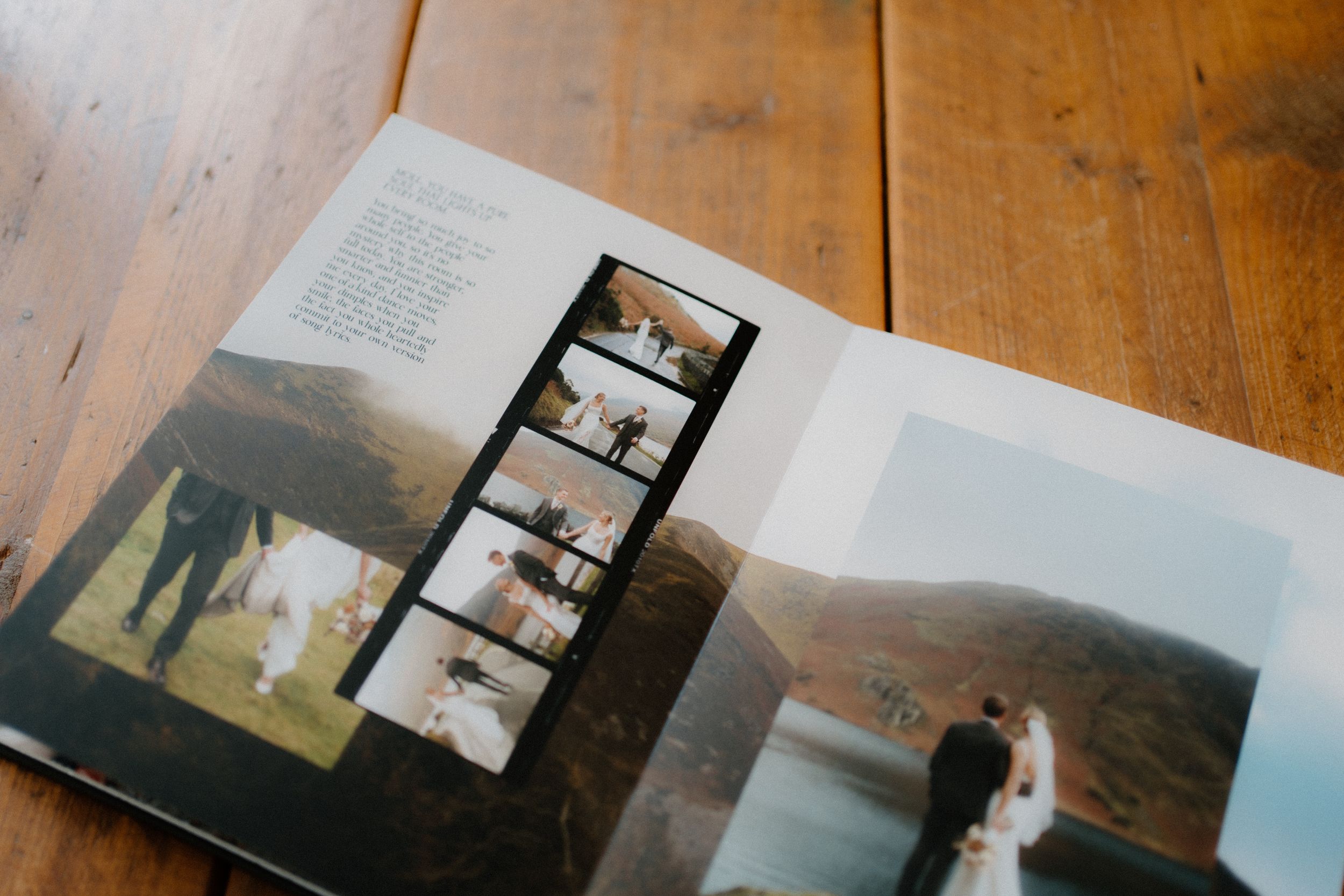 A photo album lies open on a wooden table showing wedding photographs and film strips.