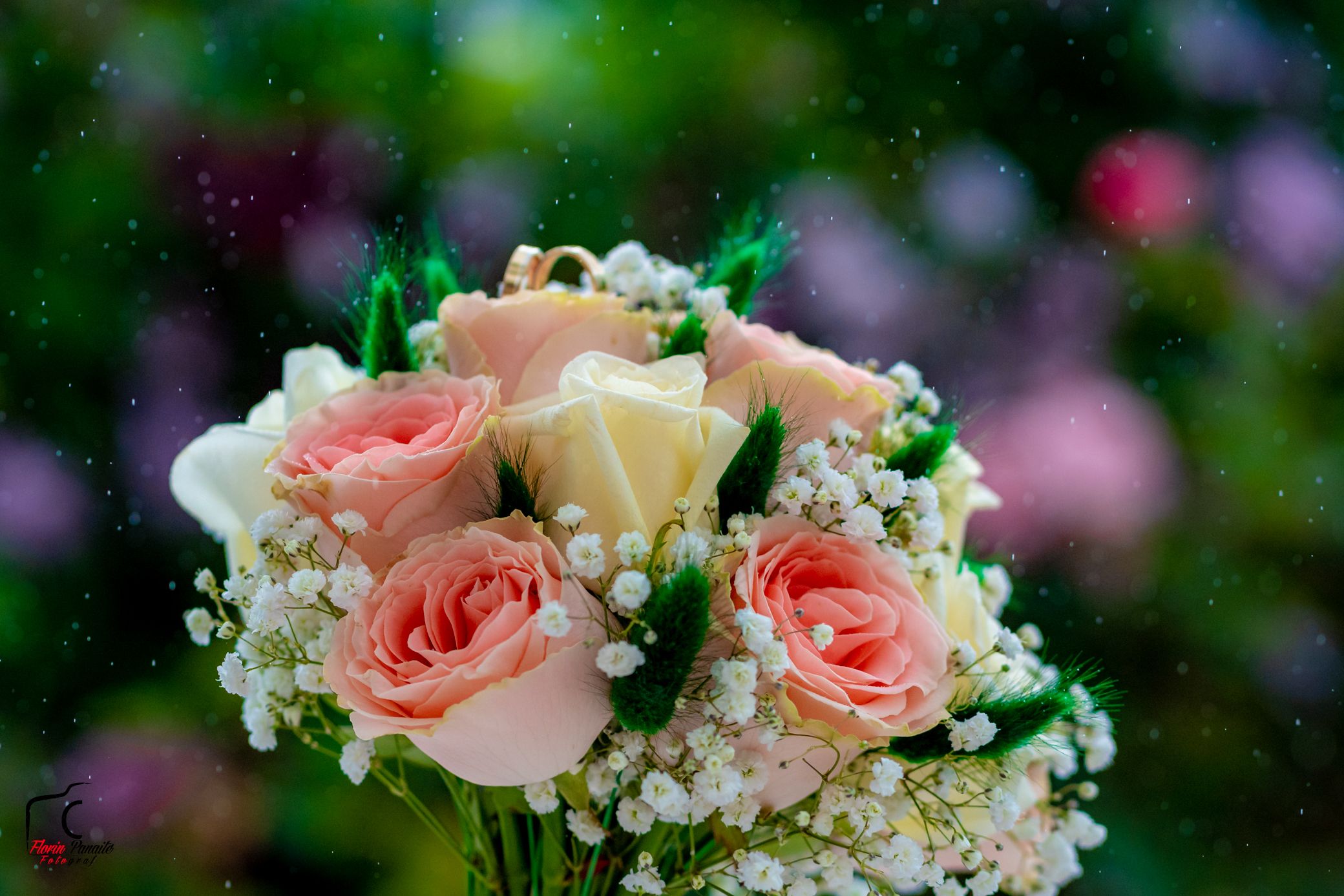 Close-up of pink roses and white baby's breath flowers with green foliage in natural lighting.