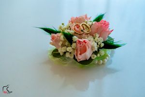 Elegant pink rose and baby's breath corsage displayed against a light blue background.
