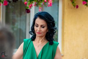 Person in vibrant green dress poses elegantly against yellow wall with pink flowers.