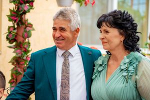 Group photo of guests in formal attire with teal and gray outfits at garden event.