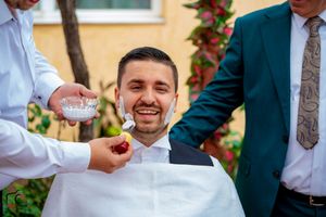 Candid moment of guests laughing at outdoor celebration with rose garden backdrop.