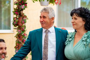 Wedding party members gathered outdoors against yellow wall with climbing red roses.
