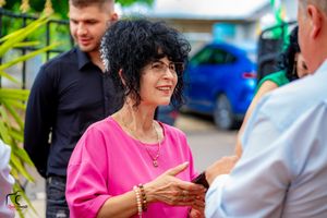 Person in bright pink top smiling during outdoor conversation.