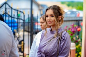 Person in lavender outfit sitting outdoors at social gathering.