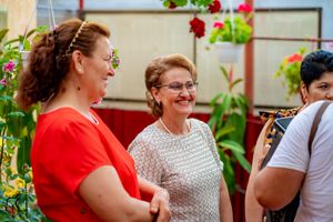 Group enjoying conversation at outdoor gathering with red flowers in background.