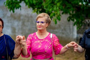 People in formal attire dance together at an outdoor celebration with trees in the background.
