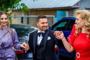 Wedding celebration with people dancing in a line wearing formal attire outdoors.
