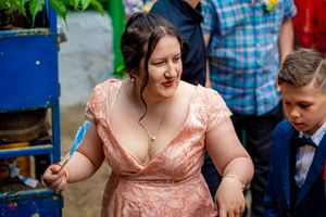 Wedding guests in colorful dresses dance together at an outdoor reception.