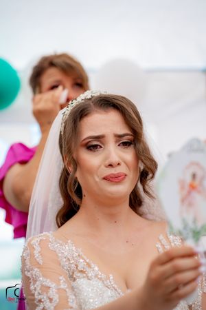 Bride in crystal headpiece and lace dress shows emotion while holding a card.