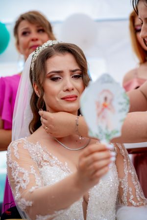 Emotional bridal preparation moment captured in a bright room with pink and teal accents.