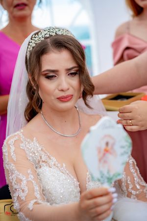 Bride in delicate lace wedding dress with crystal accessories during final preparations.