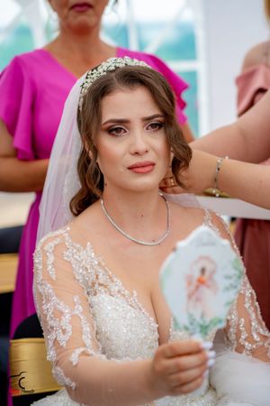 Bride wearing intricate lace wedding dress and crystal crown during pre-ceremony preparations.