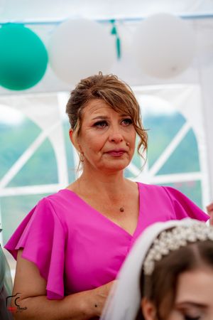 Wedding guest in bright pink dress watching emotional ceremony moment.