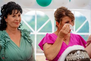 Candid reactions of wedding guests wearing pink and teal dresses during celebration.