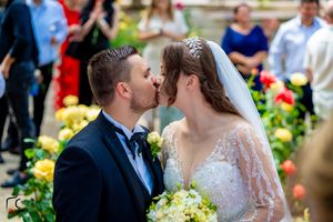Newlyweds share a tender moment in a garden surrounded by yellow and red flowers.
