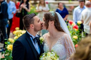 Wedding couple embracing in a beautiful garden setting with vibrant floral arrangements.