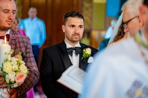 Wedding ceremony participants stand solemnly in formal attire during traditional church service.