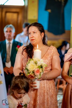 Bridesmaid in peach dress holds white and cream floral bouquet during church ceremony.