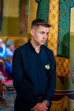 Groomsmen in black suits stand attentively during a formal church wedding service.