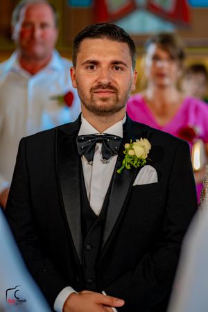 Groomsmen in classic black tuxedos with bow ties and boutonnieres at a formal wedding.
