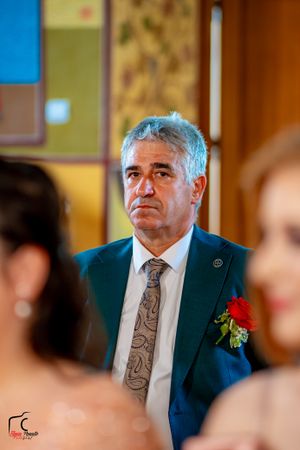 Wedding guest in formal attire observes the ceremony from their seat.