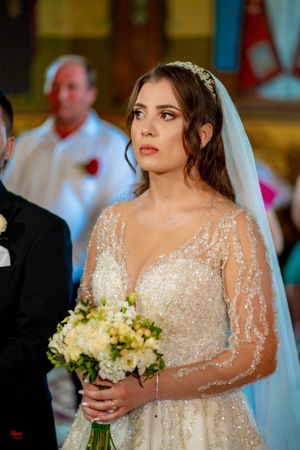 Bride in a sparkling white gown holds a bouquet of cream and yellow flowers.