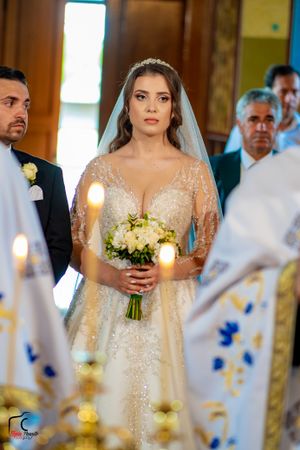 A traditional church wedding ceremony with a bride in a sparkly lace gown holding a white bouquet.