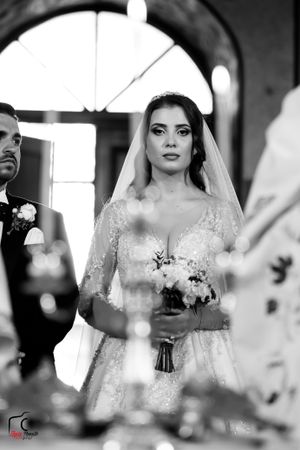 Black and white photo of a wedding ceremony in a church with candlelight and elegant decor.