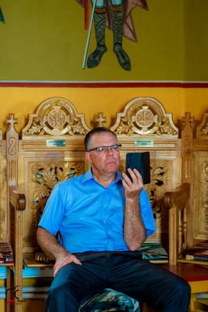 Person in light blue shirt sitting in ornate wooden chair at event venue.