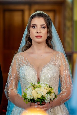 Bride in sparkly lace gown holding white and green floral bouquet.