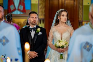 A bride and groom exchanging vows during their wedding ceremony in an ornate church setting.