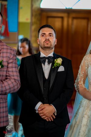 A wedding ceremony scene showing a couple in formal attire standing at the altar.