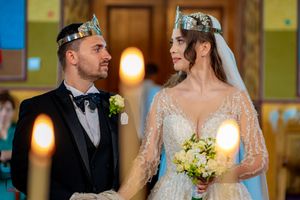 Side view of bride and groom during traditional Orthodox wedding ceremony with decorative crowns.