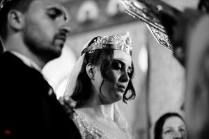 Dramatic black and white capture of Orthodox wedding crown ceremony in church.