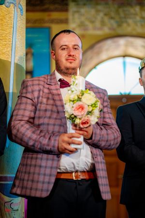 A person in a plaid jacket holds a drink during a wedding celebration.