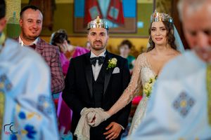 Orthodox Christian wedding ceremony with couple and priest in traditional crowns and attire.