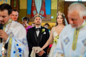 Wedding ceremony participants in traditional Orthodox Christian attire stand together during the service.