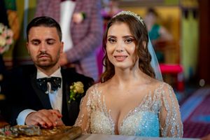 Close-up of couple during Orthodox wedding ceremony with bride in sparkly dress and traditional crown.